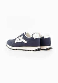 Baskets Armani Exchange bleu marine et blanc avec logo AX blanc sur les côtés et détail de talon marqué, présentées sur fond blanc.