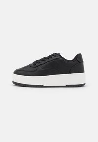 Zwarte leren sneaker met witte platformzool, ronde neus, vetersluiting aan de voorkant en geperforeerde details aan de zijkanten, met een gladde textuur.
