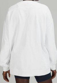 Sweatshirt bianco oversize con scollatura rotonda, maniche lunghe e polsini a costine. Tessuto liscio con una vestibilità rilassata e senza motivo visibile.