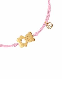 Różowy naszyjnik z cordu z złotym uroczym charmsią w kształcie niedźwiadka z wyciętym sercem oraz małym okrągłym zawieszką z logo.