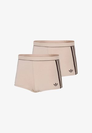 Twee beige Adidas shorts met zwarte drievoudige streepdetails aan de zijkanten en een klein zwart Adidas-logo bij de zoom.