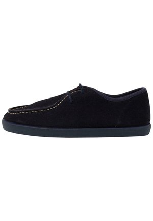 Chaussure à enfiler en suede noir avec un profil bas, présentant des coutures contrastantes, un bout arrondi et une semelle en caoutchouc flexible. Texture lisse tout au long.