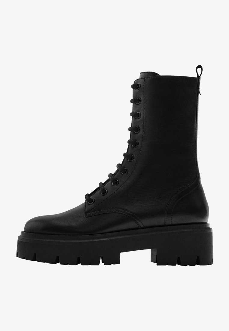 Musta nahkasaapas, jossa on kiristysnauha, korkea varsi, paksu pohja, pyöreä kärki ja huomattava ompelutyyli.