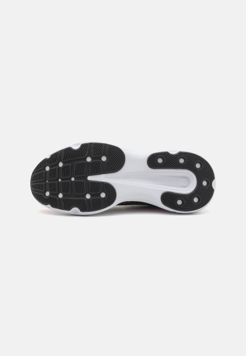 Semelle de chaussure noir et blanc avec des motifs de grip texturés, des accents arrondis distincts et des trous de drainage pour améliorer la traction et l'écoulement de l'eau.