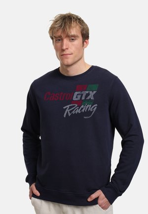 Námořnická modrá mikina vyrobená z bavlny s žebrovanými manžetami. Na přední straně se nachází logo Castrol GTX Racing v červené, zelené a bílé barvě.