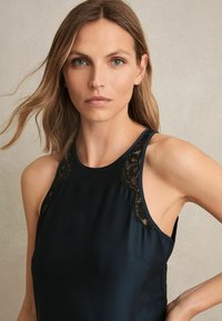 Top senza maniche blu navy con dettagli in pizzo sulle spalle, tessuto morbido, scollatura tonda e vestibilità comoda.