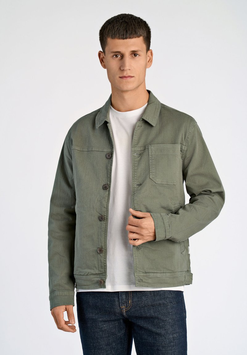 Groene katoen jasje met een knoopsluiting aan de voorkant, borstzak en kraag. Draagt over een witte T-shirt en gecombineerd met donkere jeans.