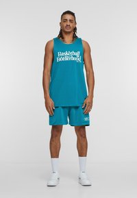 Turkise basketballdrakt med mesh-struktur, inkludert shorts. Har stor hvit tekst "Basketball Brotherhood" med logo, kombinert med hvite sneakers og sokker.