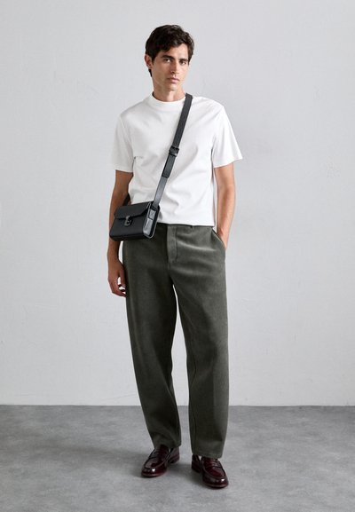 White crew neck t-shirt, olive green corduroy pants, black crossbody bag, brown leather shoes, neutral background. Smooth texture and casual design.