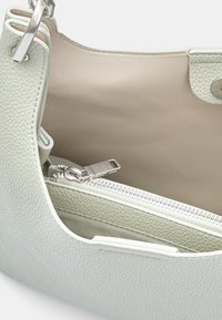 Borsa a tracolla in pelle verde chiaro con texture a granuli, dotata di una tasca con zip e accessori in argento. Interno foderato in morbido beige.