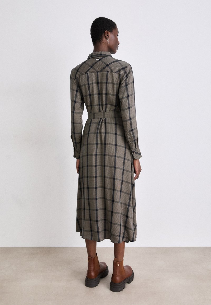 Langes karierter Kleid in Beige und Schwarz, mit einem belted Taillengürtel, geknöpften Manschetten und einem Kragen. Der Stoff hat eine strukturierte Oberfläche und fällt elegant.