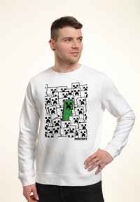 Felpa bianca con un design grafico che presenta volti pixelati in bianco e nero e un personaggio Creeper verde di Minecraft.