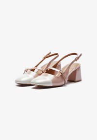 Escarpins à brides arrière bicolores en cuir verni nude et blanc. Avec un bout carré, un talon épais et une bride réglable à la cheville.