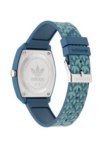 Montre numérique avec un boîtier octagonal en plastique bleu, un dos en acier inoxydable, et un bracelet en silicone vert à motifs avec des dessins de feuilles.