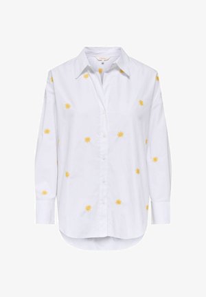 Chemise blanche à manches longues avec col pointu et petits motifs jaunes en forme de soleil dispersés sur le devant et les manches.