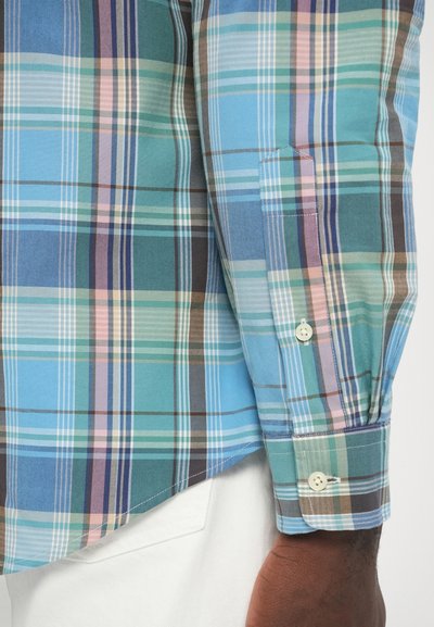 Srajca s kratkimi rokavi v karo vzorcu v odtenkih modre, zelene in rjave; ima zapenjanje na gumbe na manšetah, raznolike teksture in klasičen kroj z ukrivljenim robom.