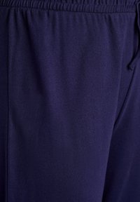Navy blue jogger pants made of soft, lightweight fabric with an elastic waistband and drawstring, featuring a smooth texture.
