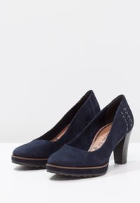 Námořnické modré semišové lodičky na vysokém podpatku s kulatou špičkou, jemným prošíváním a texturovanou gumovou podrážkou pro lepší grip.
