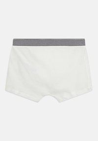 Bílé bavlněné šortky s kontrastním pruhovaným pasem. Mají hladkou texturu a klasický střih, vhodné pro volný čas.