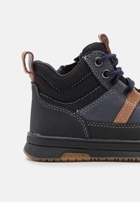 Czarno-granatowe buty typu high-top z chropowatej tkaniny, brązowymi skórzanymi akcentami oraz widocznym przeszyciem na gumowej podeszwie z logo GeoX.