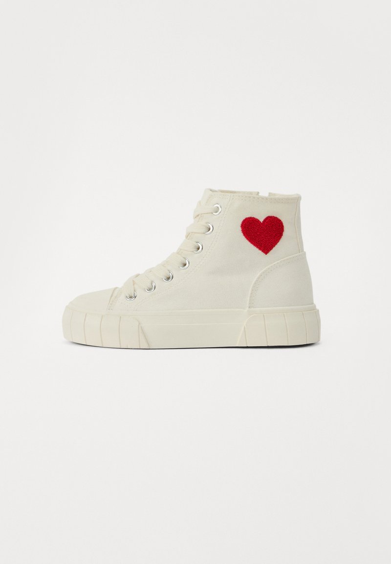 Hög-top sneakers i off-white canvas med röd hjärtbroderi på sidan. Funktioner inkluderar rund tå, gummisula och metallöglor för snörning.