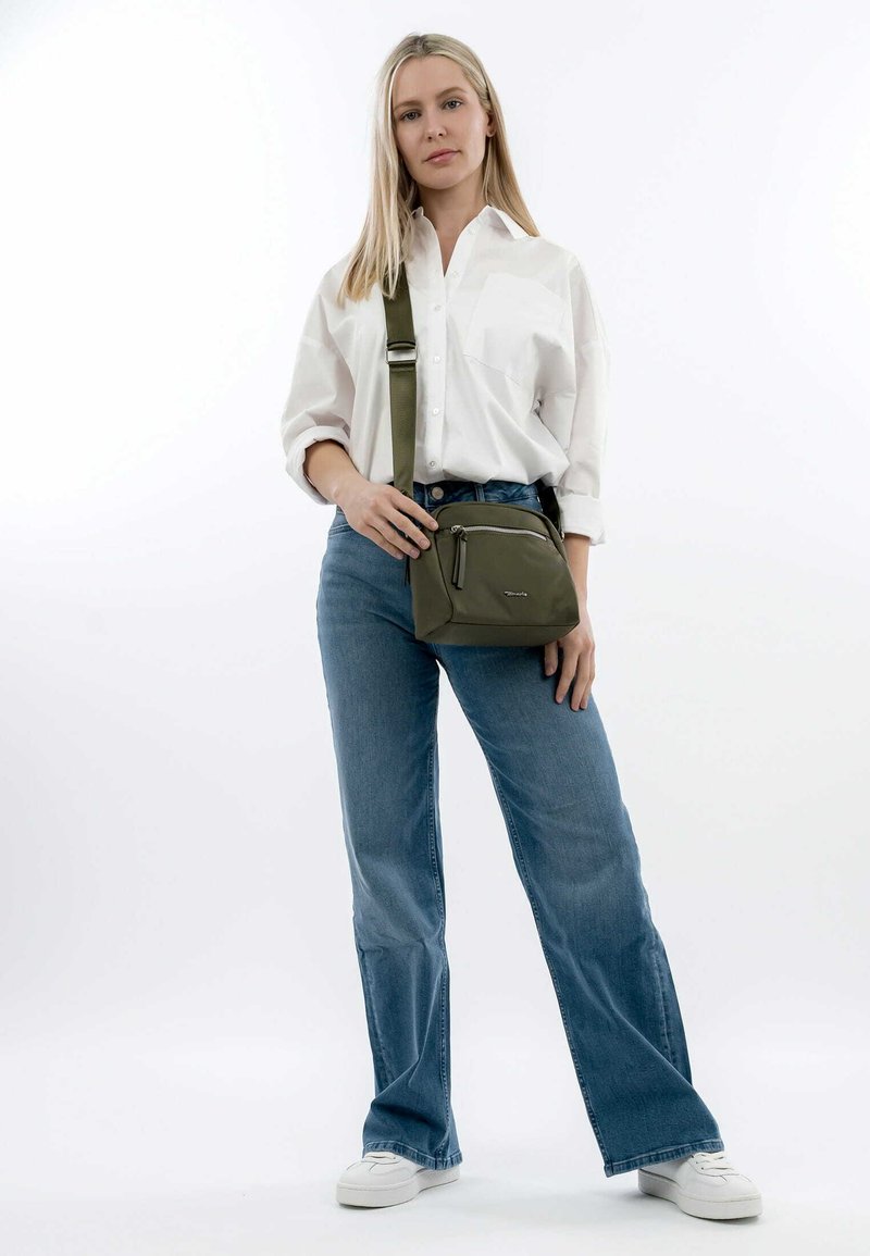 Olivgrüne Schultertasche aus Nylon, mit einem Reißverschlussfach und verstellbarem Gurt, vor einem schlichten weißen Hintergrund präsentiert.