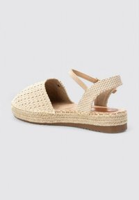 Sandalia de tela tejida beige con punta abierta, correa en el tobillo y suela de esparto texturizada. Cuenta con una plataforma y un diseño minimalista.