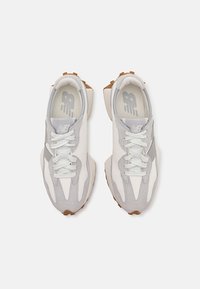 Paire de baskets New Balance blanches et grises avec lacets, vues de dessus sur un fond blanc uni.