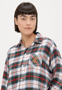 Camicia a scacchi rossa, verde e bianca con bottoni, dotata di una singola tasca sul petto con una corona dorata e le iniziali ricamate. Tessuto in cotone.