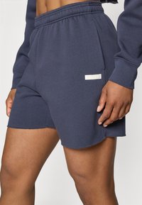 Calções em mistura de algodão azul marinho com um cós elástico, bolso lateral e um tecido texturizado apresentando um pequeno rótulo do lado direito.