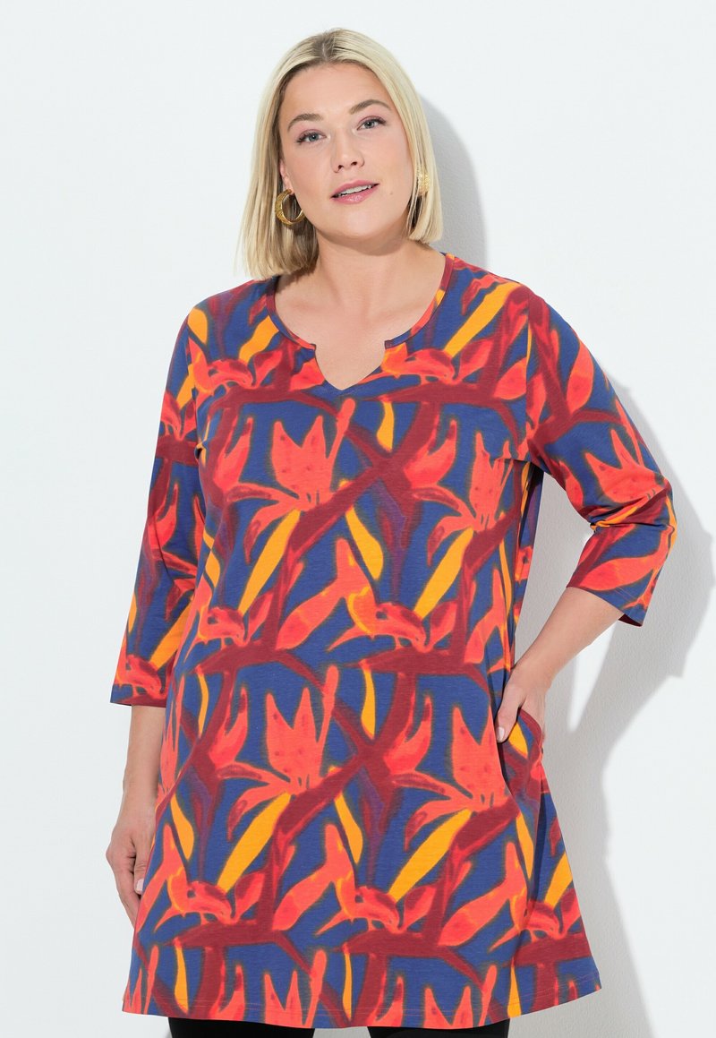 Robe bleu avec un motif floral éclatant en rouge, jaune et orange. Présente un décolleté en V et des manches trois-quarts, avec des poches latérales.
