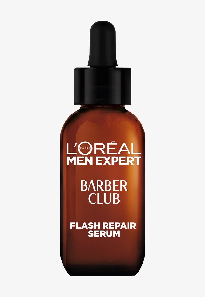 Bruine glazen fles met een zwarte druppelaar, gelabeld met "L'Oréal Men Expert Barber Club Flash Repair Serum" in witte tekst.