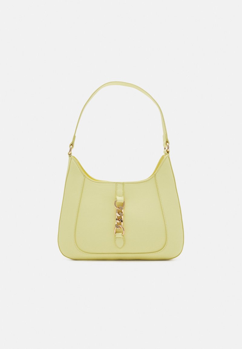 Sac bandoulière jaune pâle avec une seule sangle et un détail en chaîne dorée à l'avant, sur un fond blanc uni.