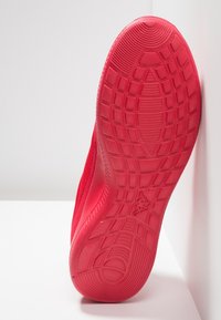 Rode sportschoenzool van textuur rubber, met een hexagonaal patroon, flexibele ontwerp en een lichte kromming bij de hiel.