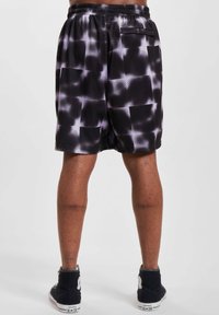 Sorte shorts med en teksturert mesh-design som har et gradientmønster av grå firkanter. Elastisk midjebånd med detaljer på baklommen.