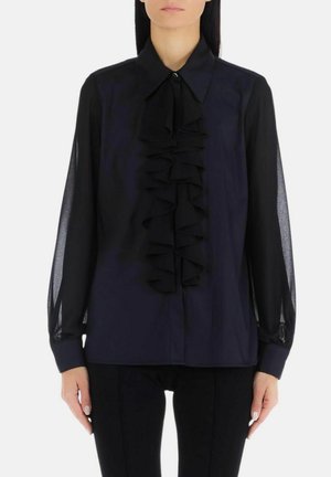 Blusa blu navy con un davanti arricciato, maniche lunghe trasparenti e colletto a punta. Presenta una chiusura a bottoni e una texture di tessuto liscia.