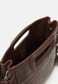 Brun tekstureret læderhåndtaske med to sidehåndtag, åbent top og en indre lomme. Har diskrete syninger og en glat, blød foring.