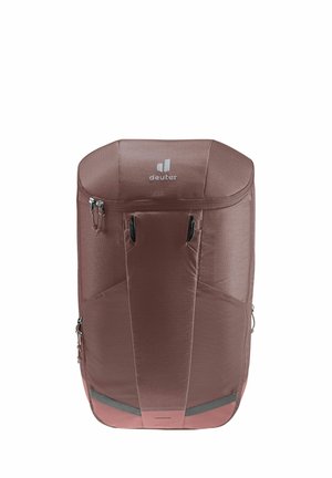 Mochila de tela marrón con una parte superior redondeada, que cuenta con un cierre de cremallera, dos bolsillos laterales y un logo sutil en la parte delantera.
