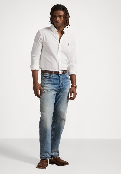White button-up shirt with a collar, light blue straight-leg jeans, brown leather belt, and brown shoes. Simple, clean design with no patterns.