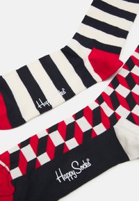Chaussettes rayées et à motifs avec des couleurs bleu marine, crème, rouge et blanc. Comprend un logo de marque en blanc. Design géométrique distinctif.