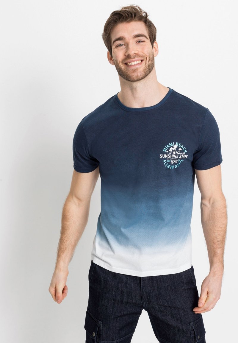 T-shirt con sfumatura blu navy e fondo bianco, scollo tondo e grafica di Miami Beach sul petto. Tessuto morbido, maniche corte.