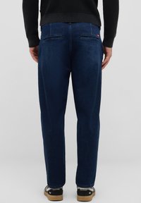 Dunkelblaue Denim-Jeans mit geradem Schnitt, die eine glatte Textur, zwei Gesäßtaschen und Kontrastnähte aufweisen.