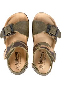 Des sandales en camouflage vert avec des accessoires noirs ajustables, des sangles en tissu texturé et une semelle en cuir naturel marron, étiquetées "billowy".