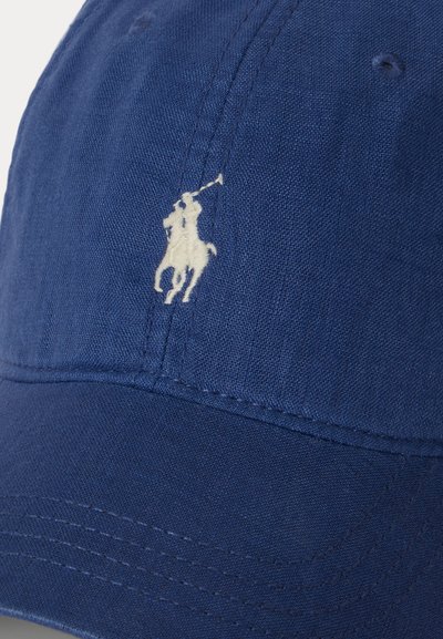 Μπλε υφασμάτινο καπέλο με λευκό κεντητό λογότυπο ενός παίκτη πόλο που ιππεύει άλογο και κουνάει ένα μαλέτι στο μπροστινό πάνελ.