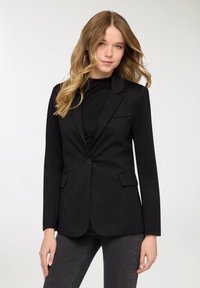 Blazer nero con design sartoriale, due tasche anteriori e chiusura con un solo bottone. Tessuto liscio e maniche lunghe.