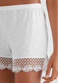 Witte katoenen shorts met een zachte textuur, voorzien van een kantafwerking aan de zoom met bloempatronen en diamandvormen.