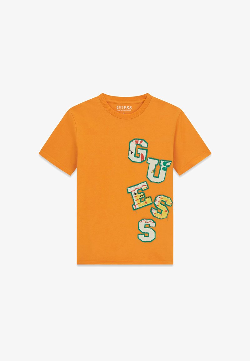 T-shirt orange à manches courtes avec des lettres multicolores en patch formant le mot « GUESS » en diagonale sur le côté avant droit.