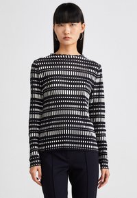 Schwarz-weißer Langarmoberteil mit Karomuster, rundem Ausschnitt, gerippter Textur und tailliertem Schnitt. Kombiniert mit dunklen Hosen.