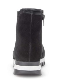Bottine en suède noir avec fermeture éclair, col rembourré, semelle en caoutchouc à rayures blanches contrastantes et bout rond.