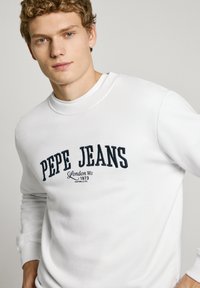 Sudadera blanca de cuello redondo con el logo "PEPE JEANS" bordado en azul marino, con puños de canalé y una textura suave. Diseño minimalista.